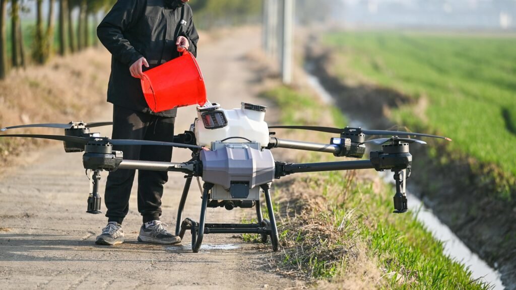 Farmer preparing large agricultural drone with liquid pesticide in sunny field.