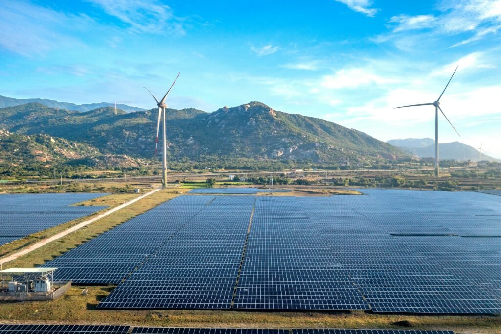A hyper-realistic aerial view captures wind turbines and solar panels spanning arid hills in Vietnam's Ninh Thuan province, a leading renewable energy hub.
​